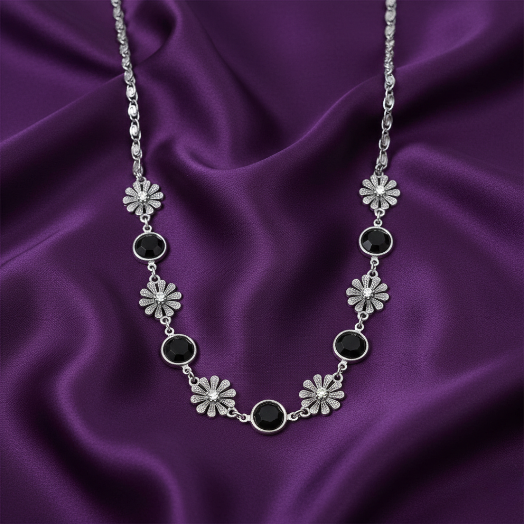 Silver necklace with black stones on a purple satin background