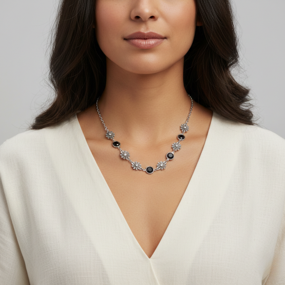 Woman wearing a floral necklace with black stones on a plain background