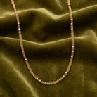 Gold chain necklace on a green fabric background