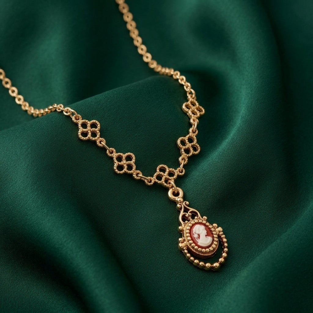Gold necklace with a red cameo pendant on a green fabric background