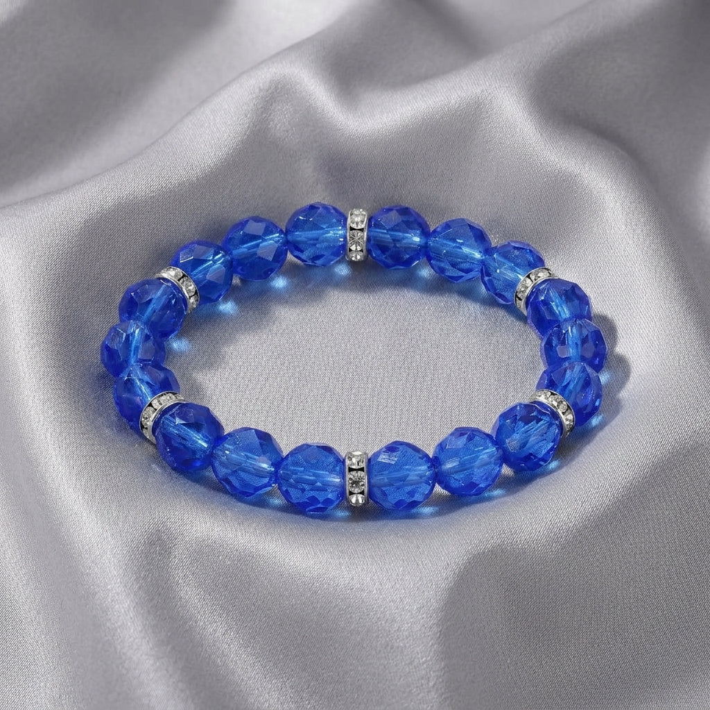 Blue beaded bracelet with silver accents on a gray fabric background