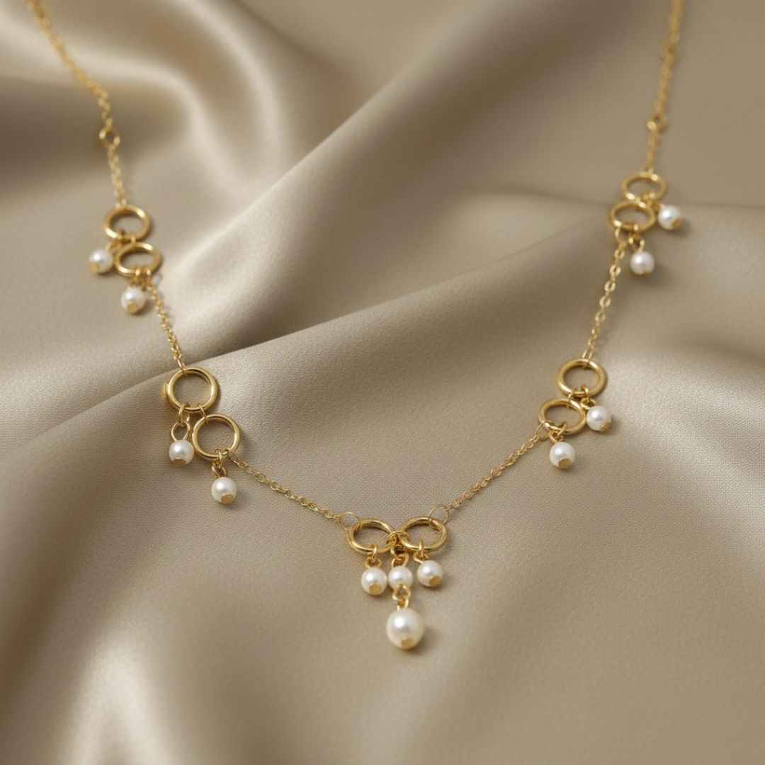 Gold necklace with pearl drops on a beige fabric background