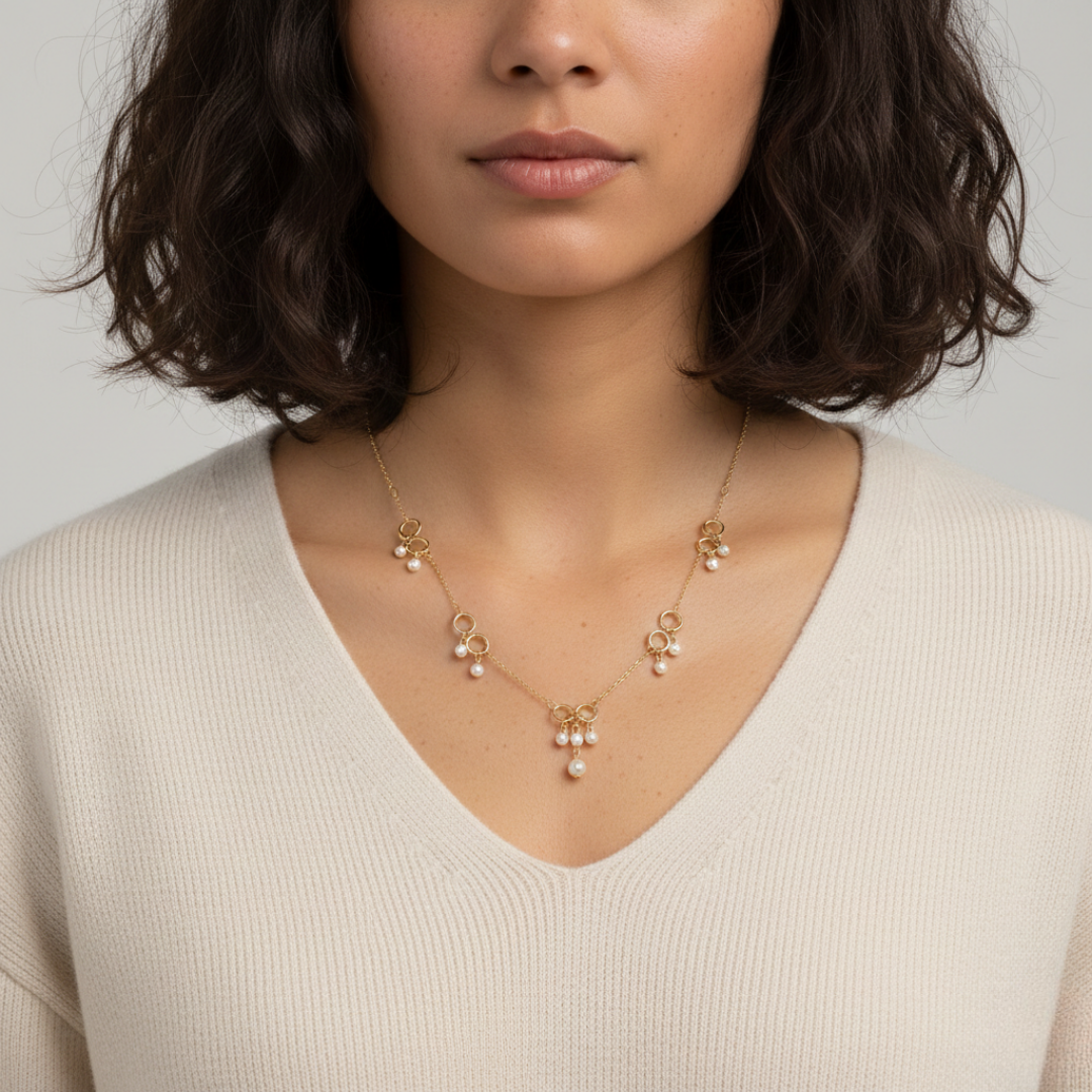 Woman wearing a delicate gold necklace with small pendants on a plain background