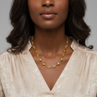 Woman wearing a gold necklace with a neutral background