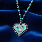 Necklace with a heart-shaped pendant featuring a horse design on a blue fabric background