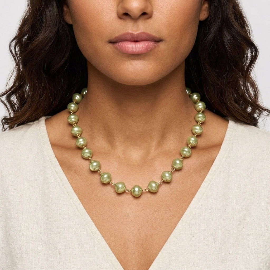 Woman wearing a green pearl necklace against a neutral background