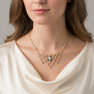 Woman wearing a gold bib necklace with a central camera pendant and clear crystals against a neutral background