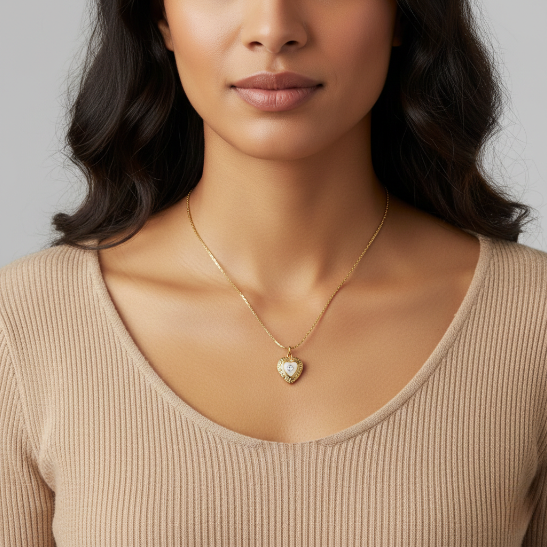 Woman wearing a gold necklace with a heart-shaped pendant and a crystal in the middle against a neutral background