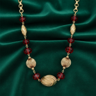 Gold necklace with red beads on a green satin background
