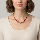 Woman wearing a gold and red beaded necklace against a neutral background