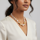 Woman wearing a pearl and gold necklace against a plain background