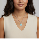 Woman wearing a necklace with a circular, turquoise horse pendant against a neutral background