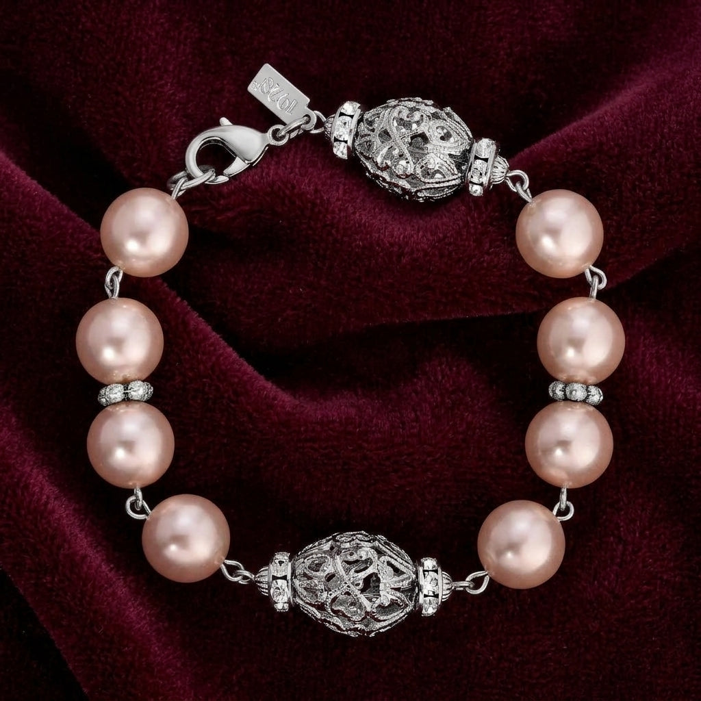 Pink faux pearl and silver tone filigree bracelet on dark burgundy fabric