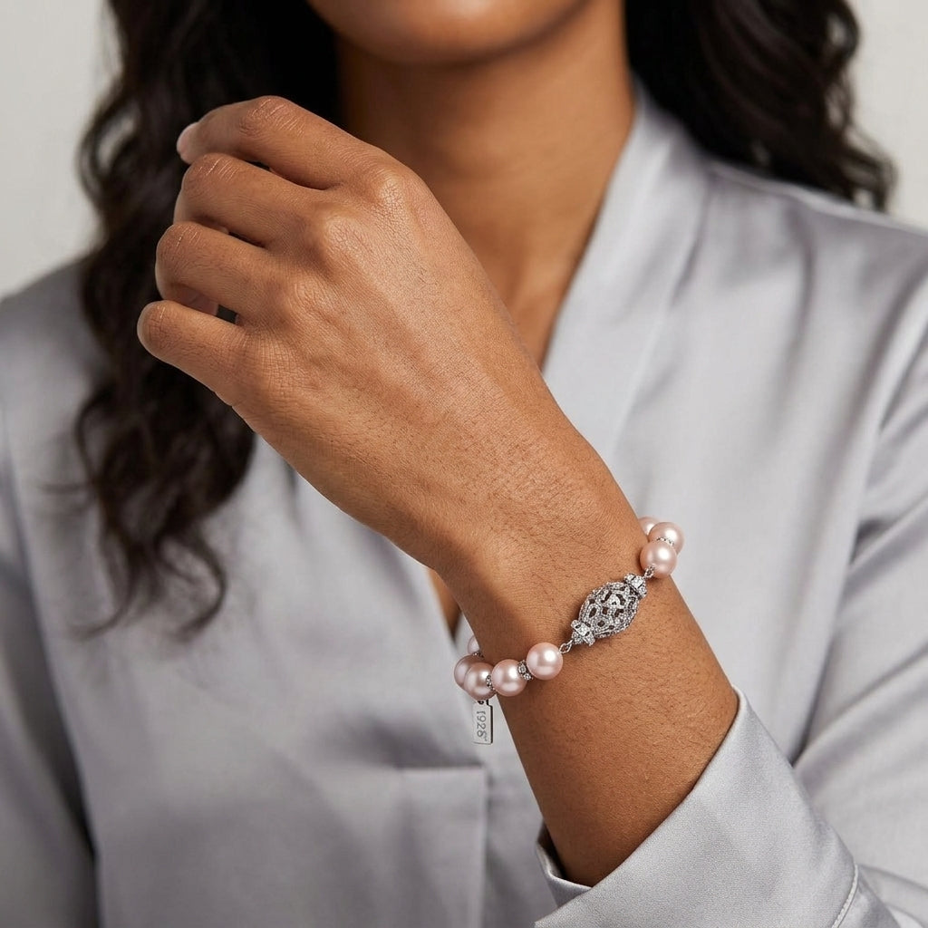 Woman wearing a pink faux pearl bracelet with silver tone filigree design