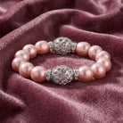 Pink pearl bracelet with silver decorative beads on a purple fabric background