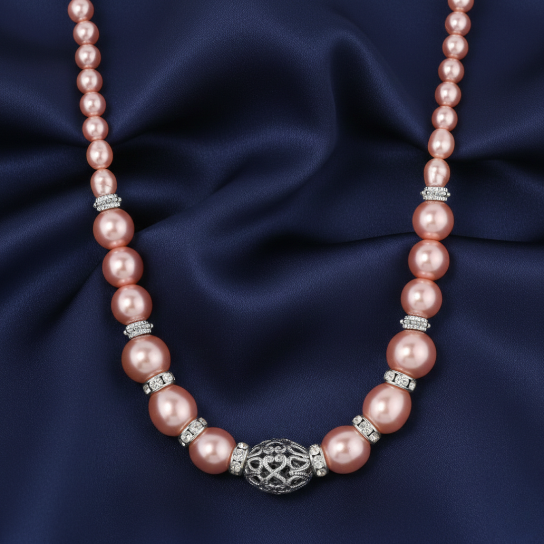 Pink faux pearl necklace with silver accents on a dark blue fabric background