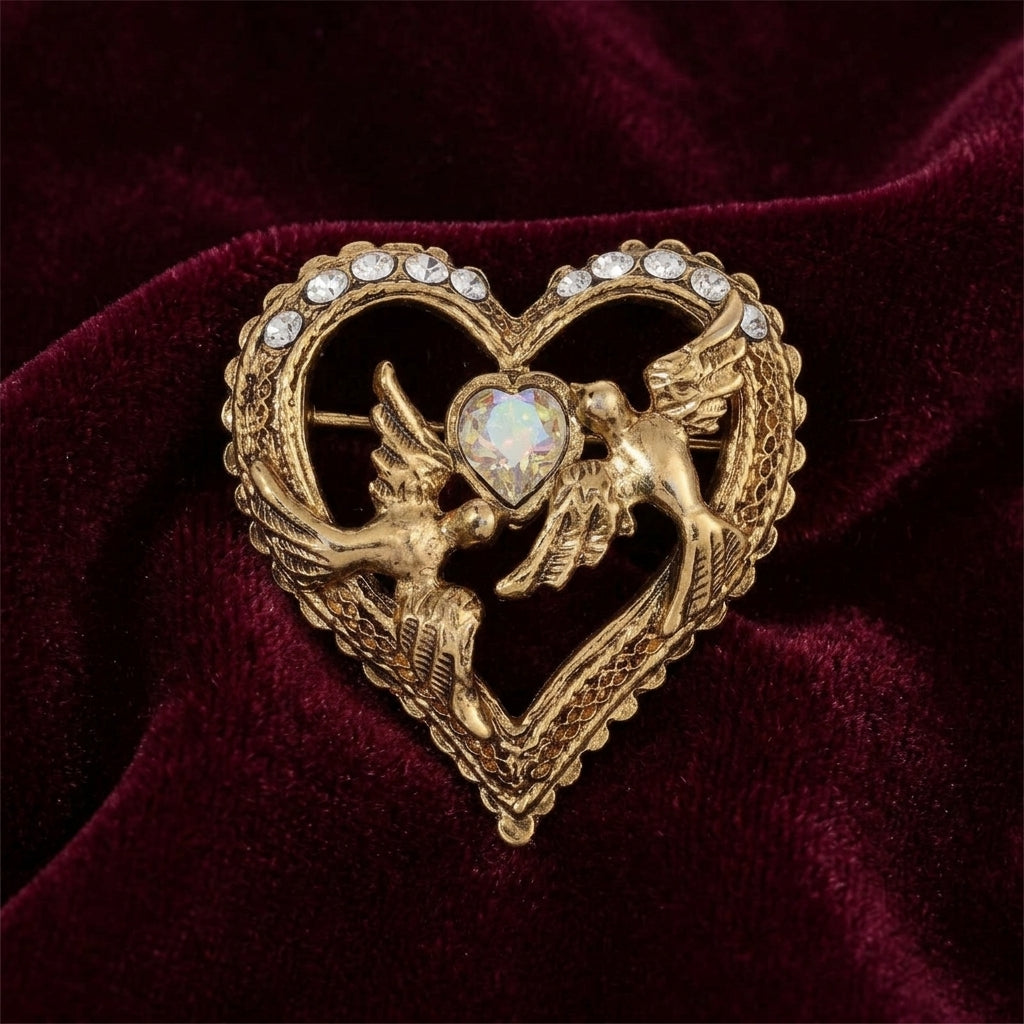 Gold heart-shaped brooch with two dove design on a burgundy velvet background