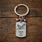 Keychain with eagle emblem and 'Made in USA' text on a wooden surface