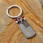 American flag keychain with red, white, and blue beaded charms on a textured stone surface
