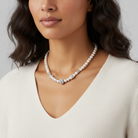 Woman wearing a faux pearl necklace against a neutral background