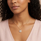 Woman in a light pink top wearing a floral crystal pendant necklace