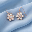 Opal Radiance Stone & Crystal Flower Drop Earrings displayed on a soft light blue fabric background.