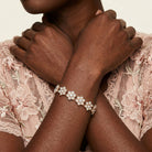 Close-up of a person wearing a delicate bracelet with opal radiance floral design on a lace fabric background