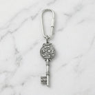 Silver key-shaped keychain with dog paws and bones design on a marble background