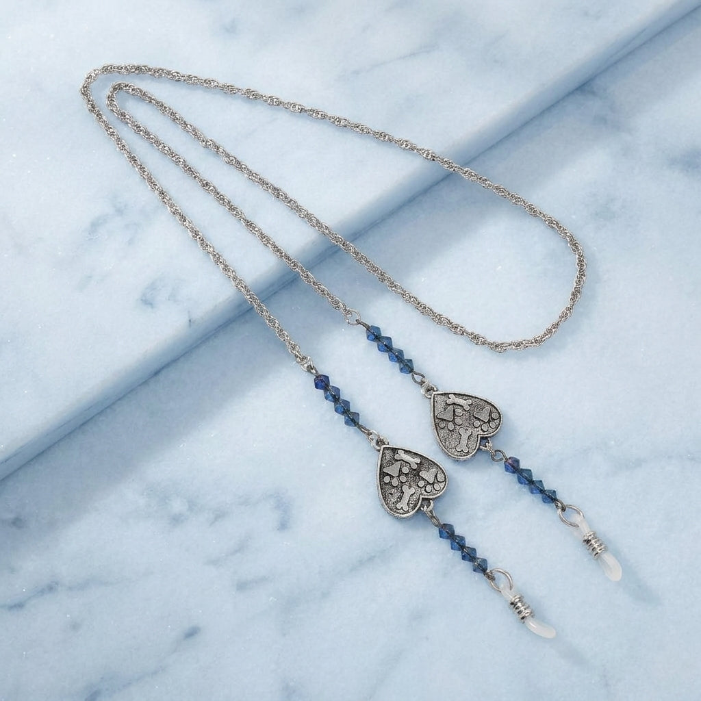 Necklace eyeglass holder with heart-shaped pendants on a marble surface