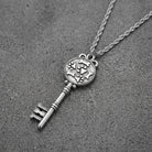 Silver key-shaped pendant with dog bones and paws motif necklace on a textured gray surface