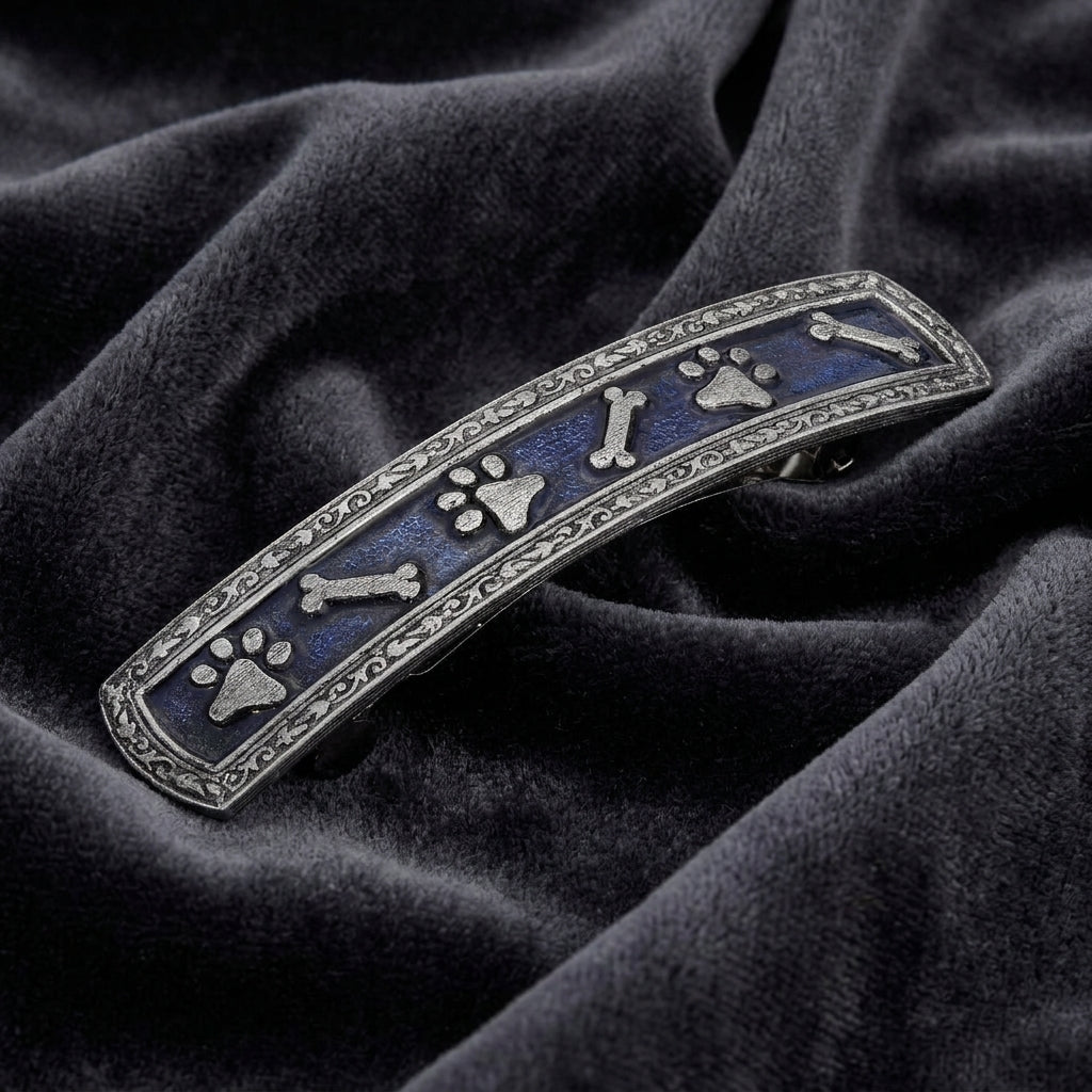 Decorative hair barrette with pet paw and bone designs on a dark fabric background
