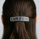 Hair barrette with pet paws and bones design in a person's hair against a neutral background
