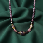 Necklace with purple and pink beads on a green fabric background