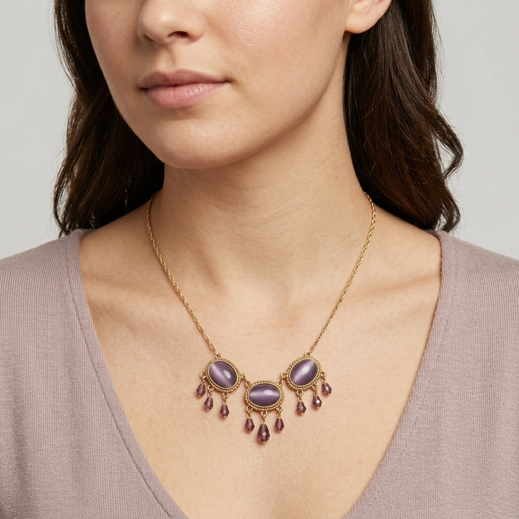 Woman wearing a gold necklace with purple stones and beads on a neutral background