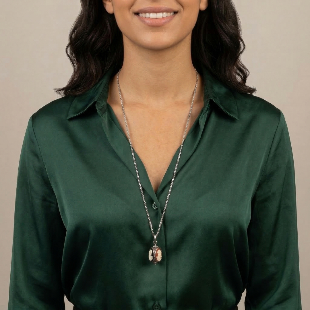 Woman wearing a green shirt and a 3-sided cameo necklace with a beige background