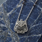 Art Deco-inspired clutch purse pendant necklace with crystal beads on a blue marble surface