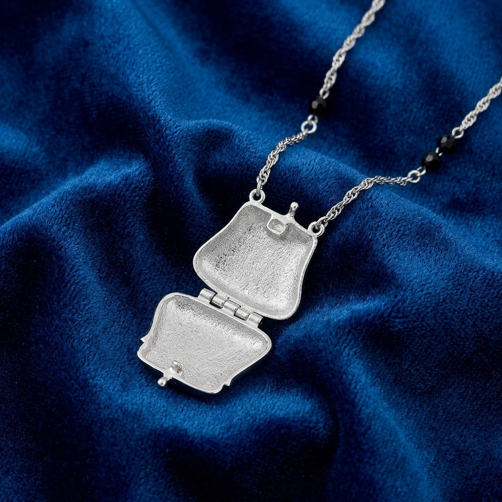 Silver opened locket necklace on a blue fabric background