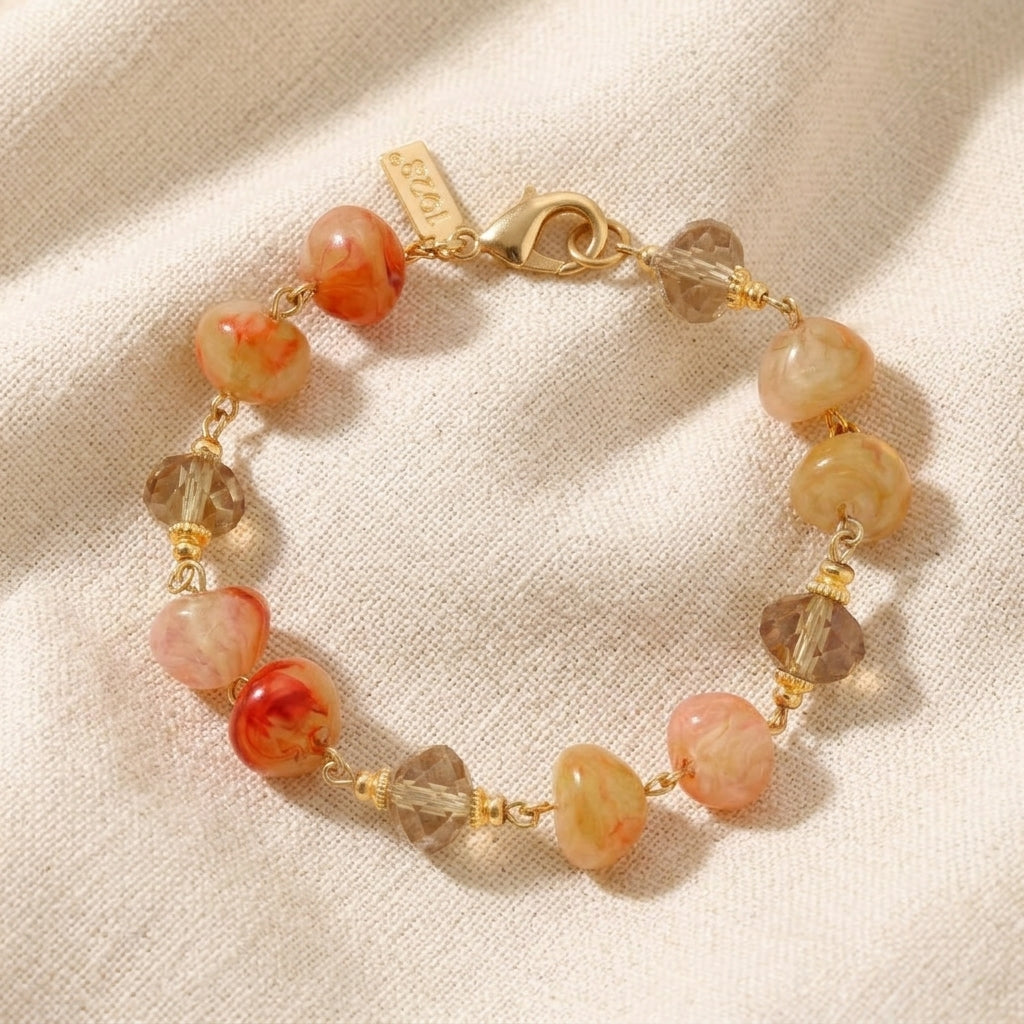 Bracelet with carnelian marbled and clear beads on a beige fabric background