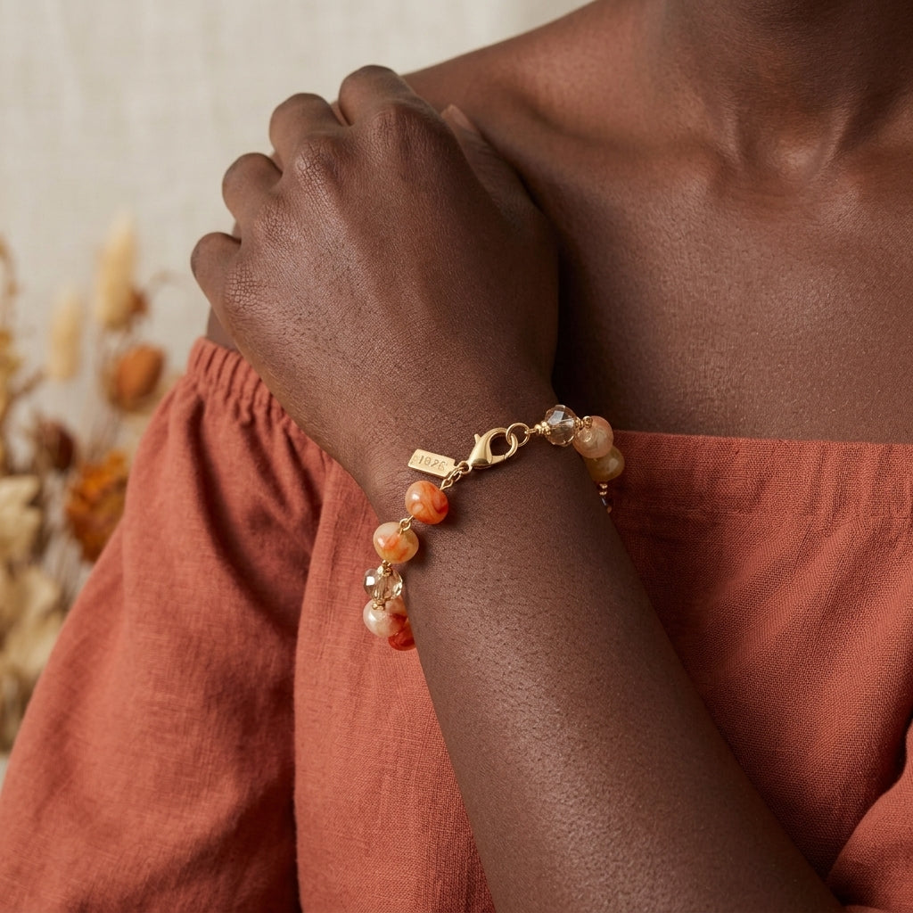 Close-up of a hand wearing a carnelian marbled beaded bracelet with a neutral background
