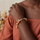 Close-up of a hand wearing a carnelian marbled beaded bracelet with a neutral background
