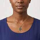 Woman wearing a gold necklace with a dog paws and bone pendant on a plain background