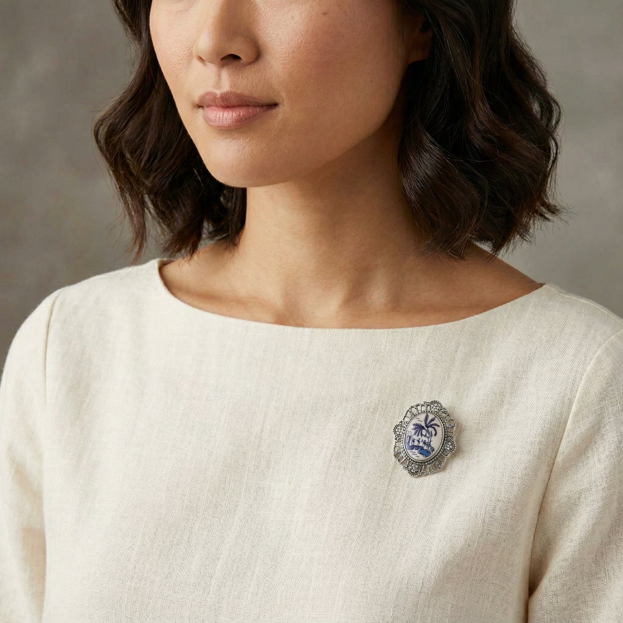 Woman wearing a blue and white brooch on a neutral background