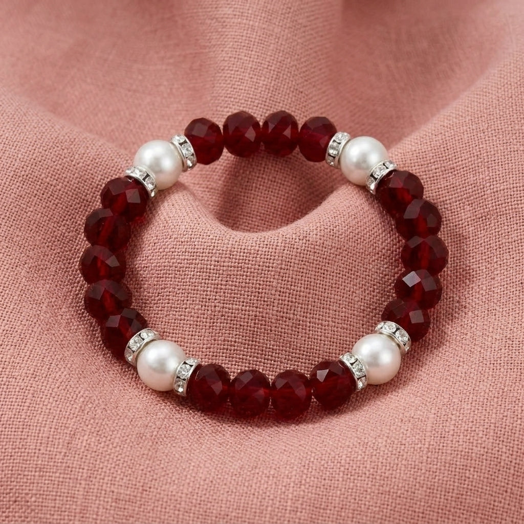 Bracelet with red beads and pearls on a pink fabric background