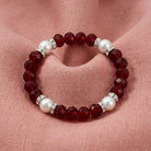 Bracelet with red beads and pearls on a pink fabric background