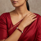 Woman wearing a red dress with a close-up of her arm and a red beaded bracelet.