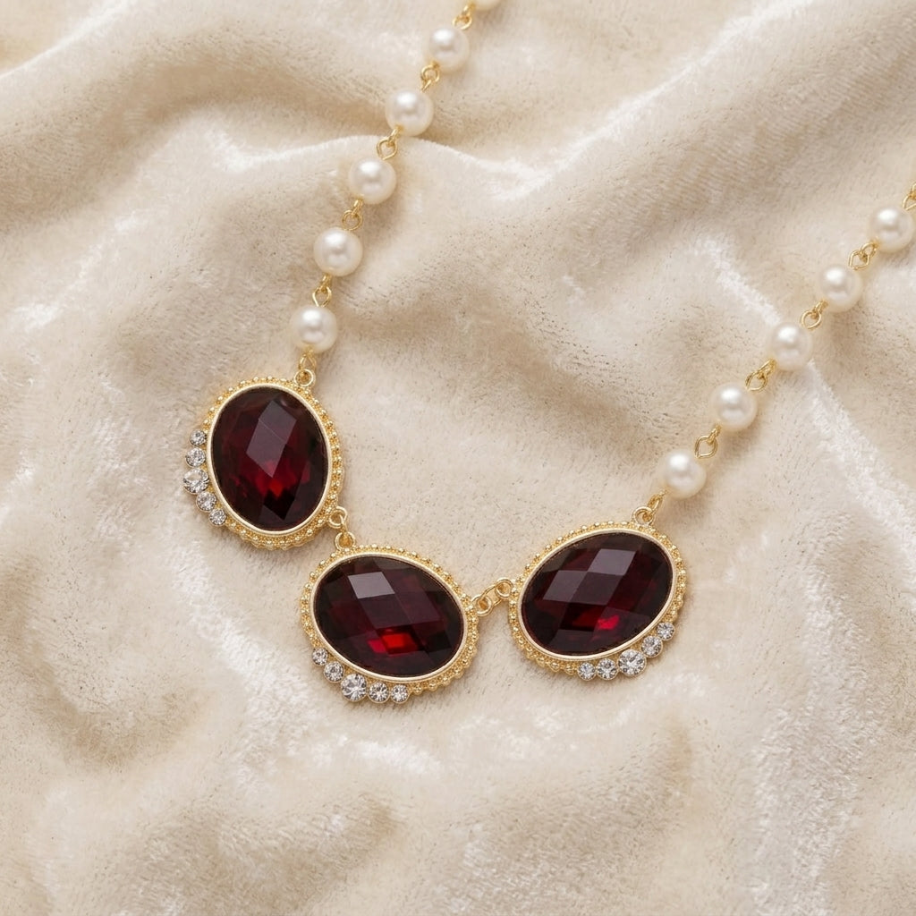 Necklace with red crystals and pearl strands on a beige fabric background