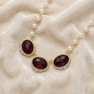 Necklace with red crystals and pearl strands on a beige fabric background