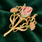 Gold brooch with pink roses on a green fabric background