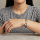 Person wearing a silver bracelet with decorative pet paws and bones elements on a neutral background