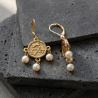 Paws & Bones Faux Pearl Dangling Earrings on a dark stone surface